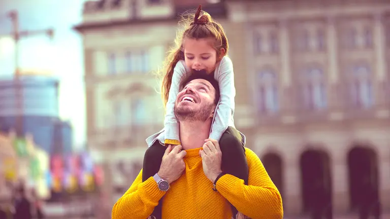 dad and daughter on his shoulders, smiling