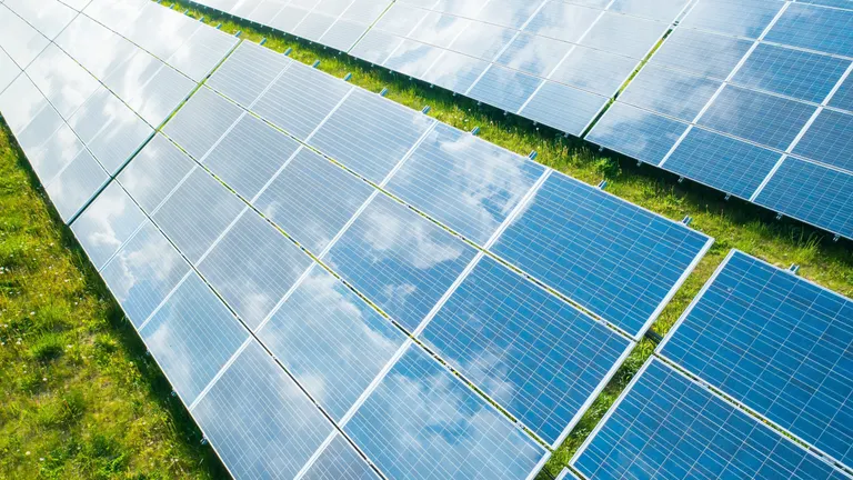 A shot of photovoltaic panels reflecting a blue sky. The panels transform solar energy into electricity