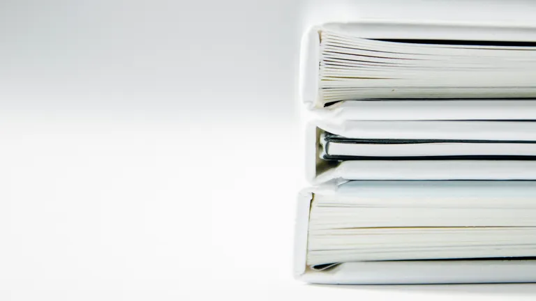 A stack of white books in front of a simple white background seen from the side